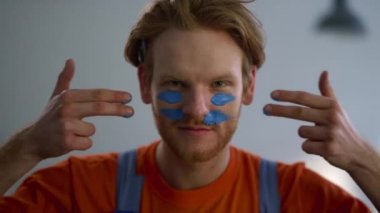 Yeni evdeki tadilat sırasında yüzüne savaş boyası süren neşeli bir adam..