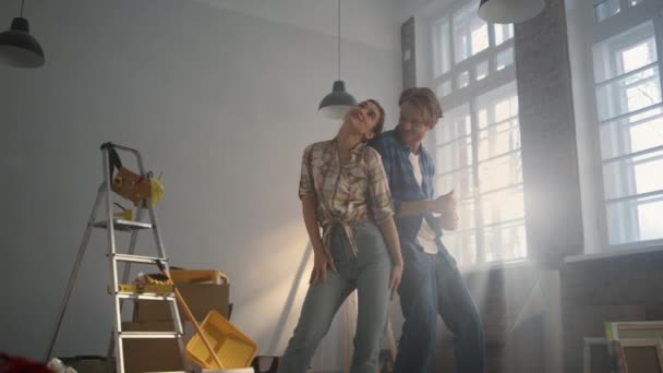 Família alegre desfrutando de reparação em casa dentro de casa. Casal alegre dançando dentro. — Vídeo de Stock