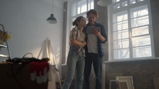 Seriöses Paar sucht Design-Projekt im Haus. Mann benutzt Tablet in neuem Zuhause. — Stockvideo