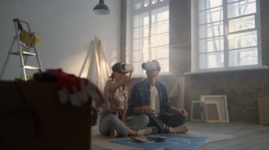 Evde video gözlüğü takarak ailesine odaklanmış. Yerde oturan çift..