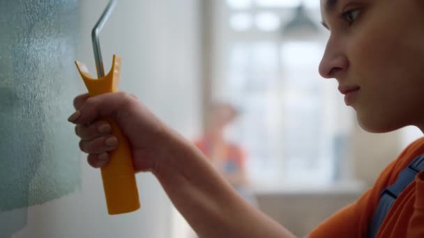 Mulher sorridente pintando com rolo para casa. Menina trabalhando como decorador dentro de casa. — Vídeo de Stock