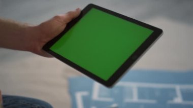 Kimliği belirsiz adam kameraya yeşil ekran gösteriyor. İçerde tasarım için tablet kullanan adam..