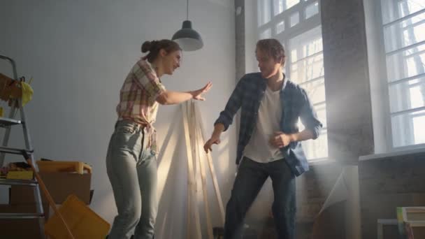 Весела пара святкує в приміщенні. Щаслива родина танцює в ремонтному будинку . — стокове відео