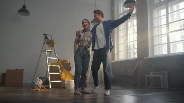 Mannen kramar kvinnan i en ny lägenhet. Par beundrar resultaten av reparation inomhus. — Stockvideo