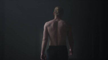 Erkek sporcu karanlık koridorda yürüyor. Spor adam çatı katına çıkıyor.