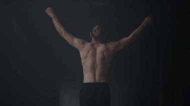 Karanlık binada yürüyen vücut geliştirici. Yoğunluk eğitiminden önce vücudu ısıtan adam