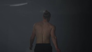 Çatı katında yürüyen atletik bir adam. Adam antrenman arasında mola veriyor. 