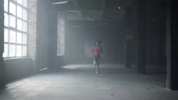 Sportvrouw training in loft gebouw. Vrouwelijke jogger hardlopen in de sportschool — Stockfoto
