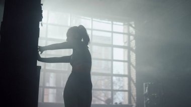 Duvarda elini uzatan bir sporcu. Formda kız antrenmandan önce omuzlarını ısıtıyor.