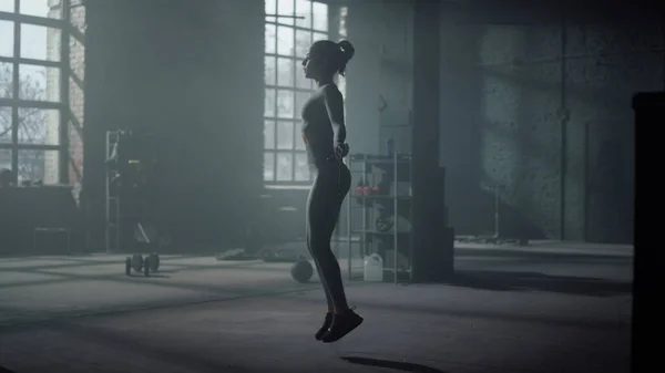 Κορίτσι πηδώντας σε σχοινάκι στο σύγχρονο γυμναστήριο. Γυναίκα που κάνει ασκήσεις πολλαπλής γυμναστικής — Φωτογραφία Αρχείου