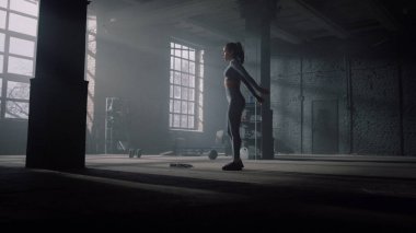 Vücut geliştirici spor salonunda kalça egzersizi yapıyor. Kız hamlelerle çömeliyor.