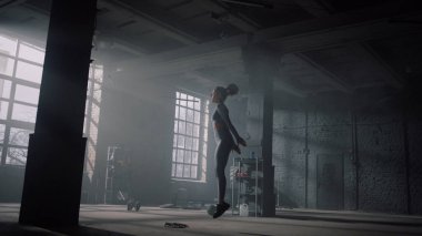 Spor kulübünde beden eğitimi gören bir kız. Sporcu çömelmeyle yüksek atlama yapıyor. 