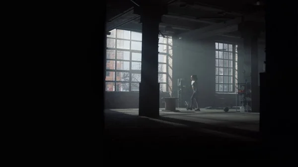 Girl doing set of box jumps in loft building. Woman having training in gym