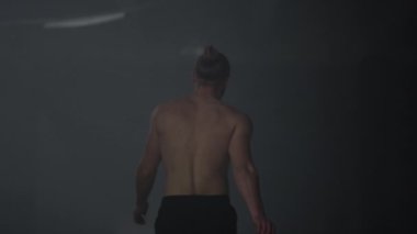 Çatı katında yürüyen atletik bir adam. Adam antrenman arasında mola veriyor. 