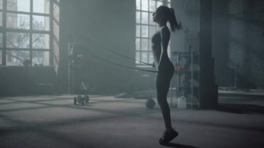 Sporcu kadın spor salonunda ip atlarken. Formda bir kadın kardiyo çalışması yapıyor.