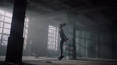 Spor kulübünde beden eğitimi gören bir kız. Sporcu çömelmeyle yüksek atlama yapıyor. 