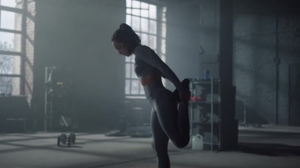 Sportkvinnan sträcker på benen innan träningen. Flicka uppvärmning muskler i gym — Stockvideo