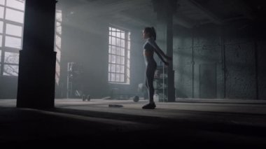 Vücut geliştirici spor salonunda kalça egzersizi yapıyor. Kız hamlelerle çömeliyor.