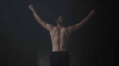 Karanlık binada yürüyen vücut geliştirici. Yoğunluk eğitiminden önce vücudu ısıtan adam