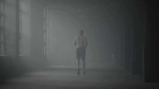 Muskulös man gör cardio träning i loft byggnad. Killen som springer i korridoren — Stockvideo