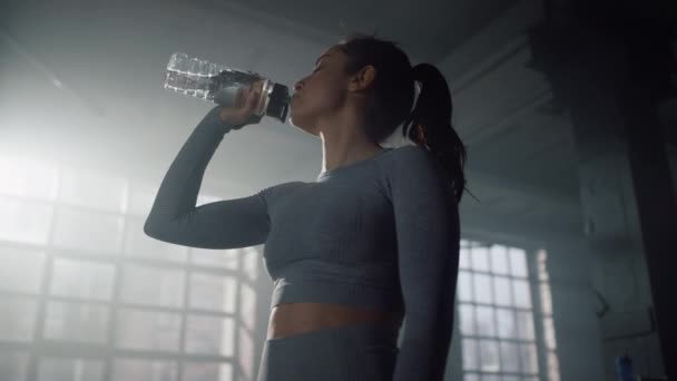 Deportiva bebiendo agua en el gimnasio. Chica descansando después de entrenar fitness — Vídeo de stock