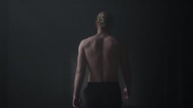 Erkek sporcu karanlık koridorda yürüyor. Spor adam çatı katına çıkıyor.