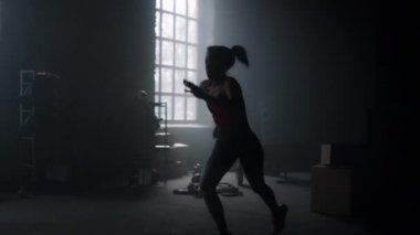 Karanlık çatı katında koşan aktif bir sporcu kadın. Spor salonunda koşan güçlü bir kadın