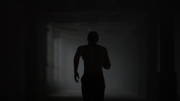 Homem de fitness a correr no corredor escuro. masculino corredor formação no loft edifício — Vídeo de Stock