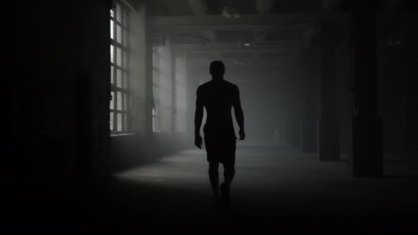 Man silhouette walking in dark corridor. Athlete taking break after workout — Stock Video