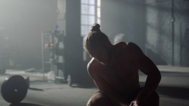 Spor malzemeleri hazırlayan adam. Sporcu halterlere tabak koyuyor. 