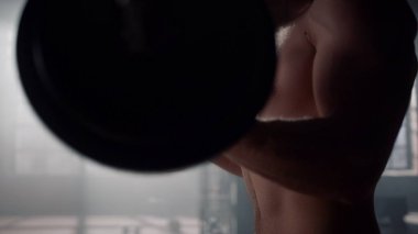 Powerlifter halter egzersizi yapıyor. Çıplak gövdeli bir adam ağırlık kaldırıyor. 