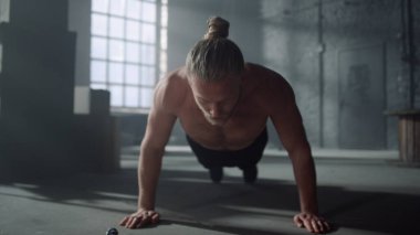 Spor yaparken şınav çeken bir sporcu. Spor salonunda fonksiyonel antrenman yapan adam