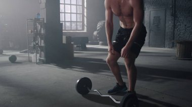 Halterle antrenmanı bitiren adam. Adam spor malzemelerini yere koyuyor.