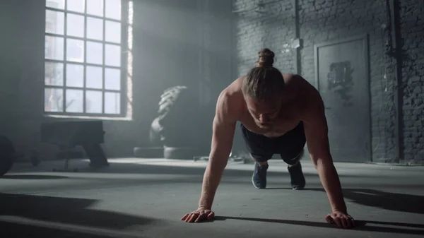 Stark man som har sport utmaning i gymmet. Manlig idrottsman gör armhävningar på golvet — Stockfoto