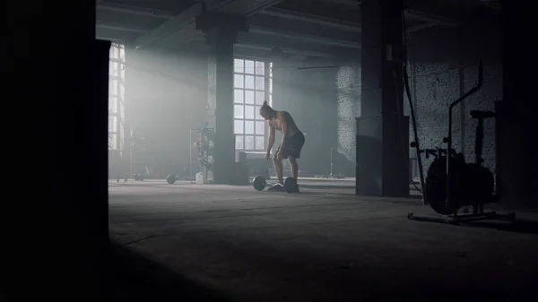 Un tipo parado en el gimnasio con equipo deportivo. Hombre tomando la barra del suelo —  Fotos de Stock