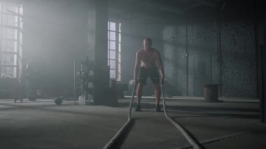 Savaş halatlarıyla egzersiz yapan bir adam. Sporcu fonksiyonel eğitim yapıyor.