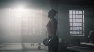 Sporcu güç egzersizinden önce derin nefes alıyor. Adam spor salonunda ağırlık kaldırıyor.
