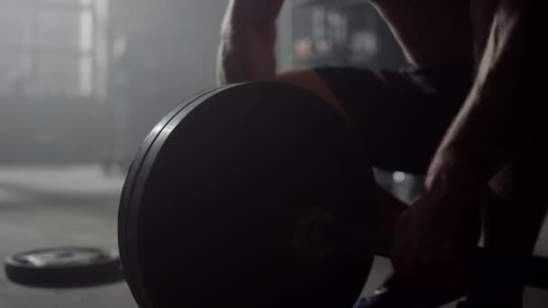 Αθλητής που προετοιμάζει αθλητικό εξοπλισμό για άσκηση. Άνθρωπος βάζοντας πλάκες στο barbell — Αρχείο Βίντεο