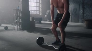 Halterle antrenmanı bitiren adam. Adam spor malzemelerini yere koyuyor.