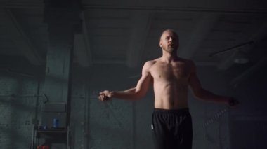 Spor salonunda atlama ipi kullanan bir adam. Adam ip atlarken zıplıyor.