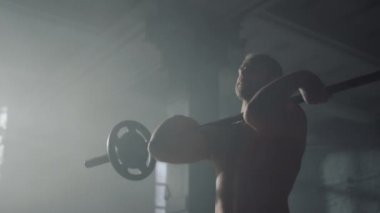 Adam ağırlık kaldırıyor. Sporcu ters tutuş halteri kıvrımı egzersizi yapıyor.