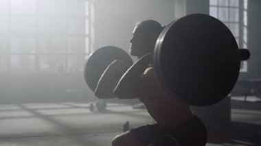 Adam ağırlık kaldırıyor. Erkek vücut geliştirici halterle çapraz uyum çalışması yapıyor.
