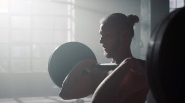 Adam antrenman sırasında ağırlık kaldırıyor. Vücut geliştirici halterle egzersiz yapıyor.