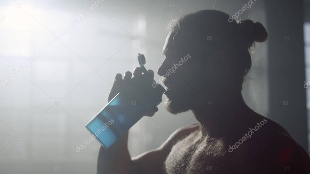 Man drinking water after training. Male bodybuilder replenishing water balance