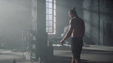 Spor malzemeleriyle spor salonunda yürüyen bir adam. Sporcu egzersizler arasında dinleniyor.