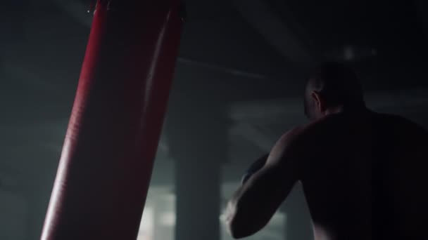 Mann beim Boxtraining im Sportverein. Kerl tritt Boxsack während des Trainings — Stockvideo