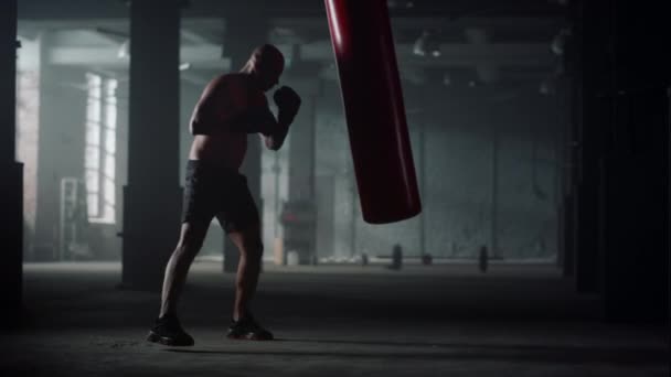 Man with muscular body punching bag in gym. Afro guy kicking sports bag — Stock Video