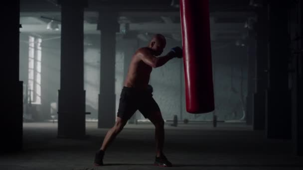 Homem batendo saco de soco durante o treino intenso. Boxer masculino praticando kickboxing — Vídeo de Stock