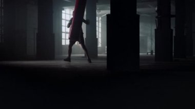 Boks antrenmanı sırasında tekme pratiği yapan bir adam. Kızgın sporcu kum torbası.