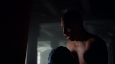 Modern spor salonunda erkek boksör tekmeleri deniyor. Kum torbasıyla dövüşen adam